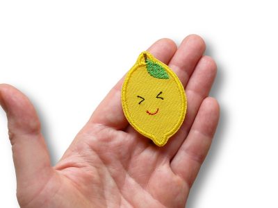 Nahaufnahme Zitronen-Patch, 6 x 4 cm gelber Baumwollstoff mit gestickter Zitrone mit Augen und Mund, Zitrone-Bügelflicken handmade Berlin Piratenbande