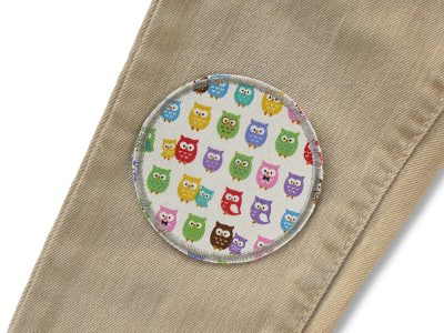 Eulen-Hosenflicken aus cremefarbenem Baumwollcanvas auf eine Kinderhose aufgebügelt, Ø 7 cm, buntes Mini-Eulen-Allover-Muster auf Creme, Bügelflicken für helle Kinderhosen und Erdtöne handmade Berlin