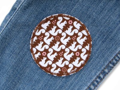 Eichhörnchen Hosenflicken auf Kinderhose aufgebügelt, brauner Baumwollstoff Ø 7 cm mit weißem Eichhörnchen-Allover-Muster, Bügelflicken handmade Berlin Piratenbande