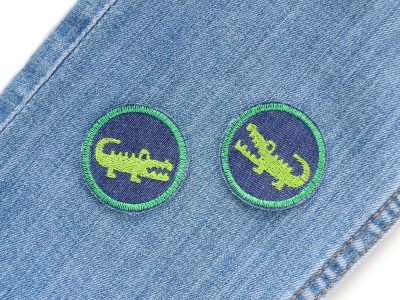 Krokodil Mini-Jeansflicken auf einer Jeanshose, dunkelblaue Patches Ø 4 cm mit gesticktem grünen Krokodil, Mini-Bügelflicken für Schulranzen Jacken Caps handmade Berlin Piratenbande