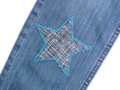 Gitter-Stern-Bügelflicken auf Jeanshose aufgebügelt, weißer Baumwollstoff 10 x 10 cm mit schwarzem Gitternetz und Petrol-Umrandung, Hosenflicken Kinderhosen reparieren Piratenbande Berlin