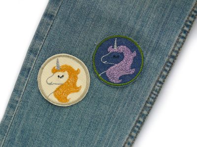 Einhorn-Jeansflicken in 2 Varianten auf Hosenbein aufgebügelt – hell mit goldgelber Mähne und dunkelblau mit fliederfarbener Mähne – Ø 5,5 cm, Einhorn-Bügelflicken handmade Berlin