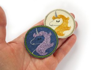 Zwei Einhorn-Patches auf Hand: heller Jeansstoff goldgelbe Mähne und dunkelblauer Jeansstoff fliederfarbene Mähne, Ø 5,5 cm, Einhorn-Jeansflicken zum Aufbügeln handmade Berlin