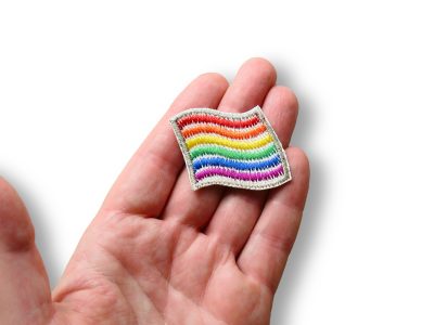 Pride Aufnäher Regenbogen Flagge 4 x 3,5 cm auf Hand, weißer Jeans mit Regenbogenfarben Flaggenform, Bügelflicken handmade Berlin