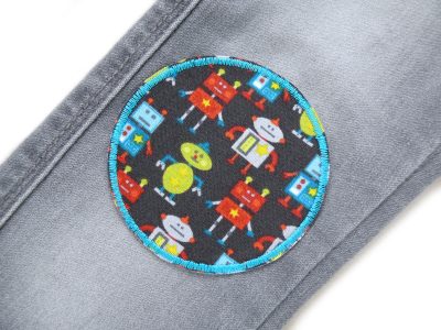 Roboter Hosenflicken Ø 8 cm auf Kinderhose aufgebügelt, dunkelgrauer Baumwollstoff mit vielen bunten Robotern, Knieflicken handmade Berlin Piratenbande