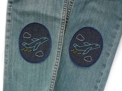 Flugzeug-Knieflicken auf Kinderhose aufgebügelt, dunkelblauer Jeansstoff 8 x 10 cm mit gestickten Flugzeugen, Hosenflicken Kinderhosen reparieren Piratenbande Berlin