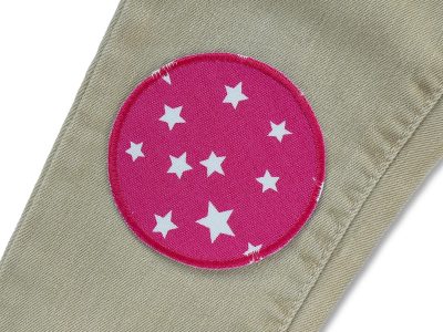 Pinker runder Stern-Hosenflicken auf Kinderhose aufgebügelt, Baumwollcanvas Ø 8 cm mit weißen Sternchen, Bügelflicken Kinderhosen reparieren Piratenbande Berlin