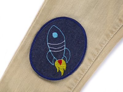 Raketen-Knieflicken auf Kinderhose aufgebügelt, dunkelblauer Jeansstoff 8 x 10 cm mit bunten Raketen gestickt, Hosenflicken Kinderhosen reparieren Piratenbande Berlin