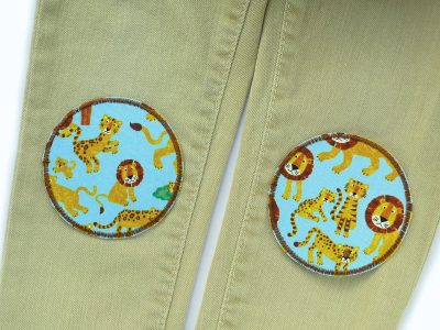 Löwe und Tiger Hosenflicken auf Kinderhose aufgebügelt, hellblauer Baumwollstoff Ø 8 cm mit Safari-Tiermuster, Bügelflicken Knieflicken handmade Berlin Piratenbande