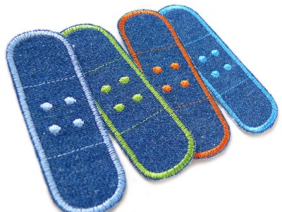 Nahaufnahme 4er Set Jeans Trostpflaster blau, 8,5 x 3 cm Pflasterform mit Umrandung in Orange Blau Blassblau Hellgrün, Hosenpflaster Bügelflicken handmade Berlin Piratenbande
