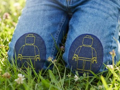 Gelbe Bausteinmännchen-Knieflicken auf Kinderhose aufgebügelt, dunkelblauer Jeansstoff 8 x 10 cm mit gelben Spielfiguren, Bügelflicken Kinderhosen reparieren Piratenbande Berlin