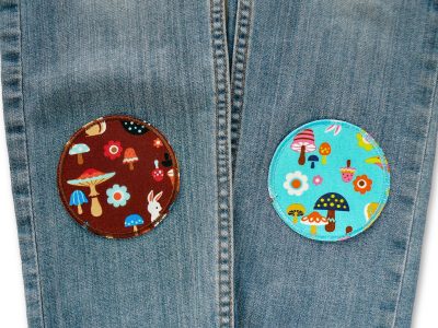 Waldfreunde Hosenflicken braun und türkis auf einer Kinderjeans aufgebügelt, Baumwollcanvas Ø 8 cm mit Waldtier-Allover-Muster Igel Hase Blumen, Knieflicken Bügelflicken handmade Berlin Piratenbande