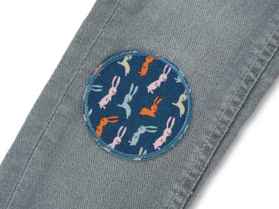 Häschen-Bügelflicken auf Kinderhose aufgebügelt, dunkelgrauer Baumwollstoff Ø 7 cm mit bunten Hasen Allover-Muster, Hosenflicken Kinderhosen reparieren Piratenbande Berlin