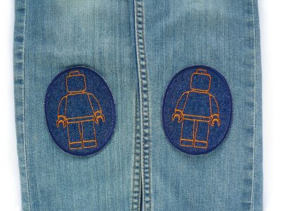 Orangefarbene Bausteinmännchen-Knieflicken auf Kinderhose aufgebügelt, dunkelblauer Jeansstoff 8 x 10 cm mit gestickten Spielfiguren, Hosenflicken Kinderhosen reparieren Piratenbande Berlin