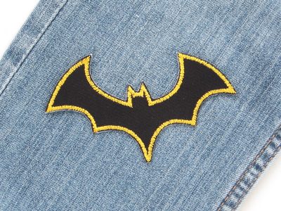 Fledermaus Bügelflicken schwarz auf Jeanshose aufgebügelt, 10 x 6 cm schwarzer Baumwollstoff mit goldgelber Umrandung, Halloween-Aufnäher handmade Berlin Piratenbande
