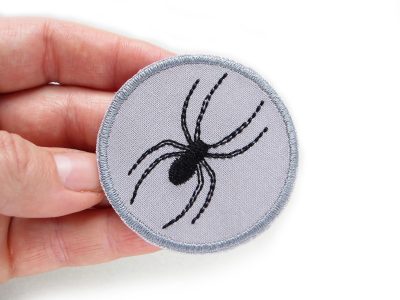 Gestickter Spinnen-Bügelflicken auf grauem Baumwollstoff, schwarze Spinne Ø 5,5 cm, Halloween-Patch oder Gothic-Aufnäher, Piratenbande Berlin