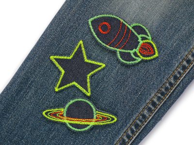 Weltall-Patches Set auf Kinderhose aufgebügelt, Neon-Rakete Neon-Saturn Neon-Stern auf dunkelblauem Jeansstoff, Bügelflicken Kinderhosen reparieren Piratenbande Berlin