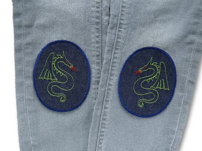 Zwei Drachen-Knieflicken aus dunkelblauem Jeansstoff auf Jeanshose aufgebügelt, 8 x 10 cm, grünes Drachen-Allover, Bügelflicken handmade Berlin Piratenbande