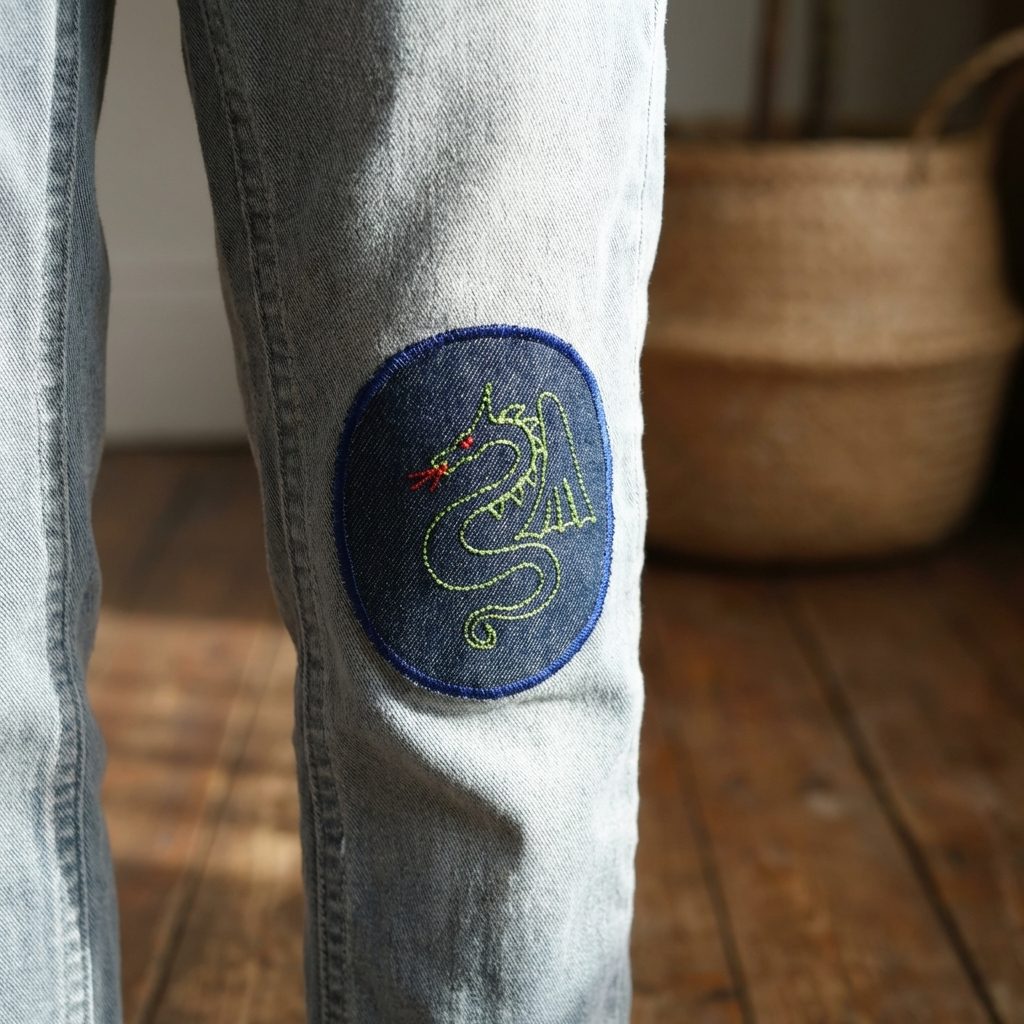grüner Drache Knieflicken aus dunkelblauem Jeansstoff auf einer Kinderhose, aufgestickter und feuerspeiender Drache Hosenflicken für Kinder, 8 x 10 cm, handmade in Berlin