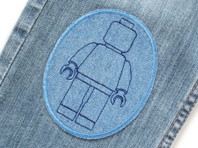 Mittelblaue Bausteinmännchen-Knieflicken auf Kinderhose aufgebügelt, Jeansstoff 8 x 10 cm mit dunkelblauen Spielfiguren, Hosenflicken Kinderhosen reparieren Piratenbande Berlin