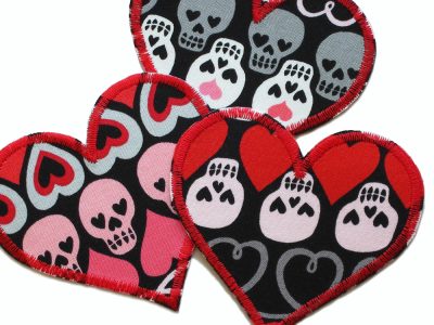 Nahaufnahme Herz Aufnäher Skull, schwarzer Baumwollstoff 8,5 x 8 cm mit bunten Totenköpfen und Herzen Allover, herzförmiger Bügelpatch Unikat handmade Berlin