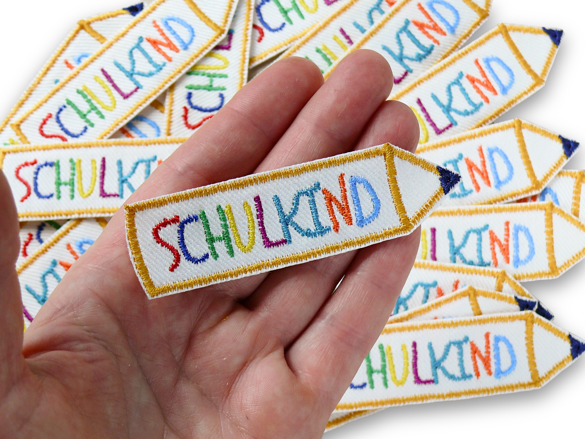 Nahaufnahme Schulkind Aufnäher, gestickter Bleistift 9 x 2,5 cm mit Regenbogen-Buchstaben auf weißem Jeans, Bügelpatch handmade Berlin