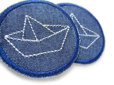 Nahaufnahme Papierschiffchen Jeansflicken hellgrau Ø 5 cm dunkelblauer Jeansstoff mit hellgrau gesticktem Boot, Mini-Bügelpatch handmade Berlin Piratenbande