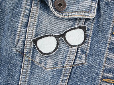 Nerdbrille Patch auf Jeansjacke aufgebügelt, hellblauer Jeansstoff 8 x 3 cm mit gestickter schwarzer Brille, Bügelflicken handmade Berlin Piratenbande