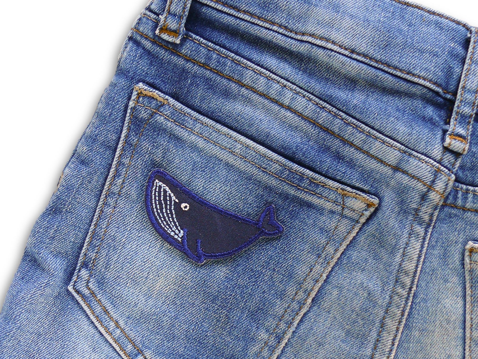 Mini Buckelwal Bügelpatch auf Gesäßtasche einer Jeans aufgebügelt, dunkelblauer Canvas 6 x 2,5 cm, Wal-Accessoire handmade Berlin Piratenbande