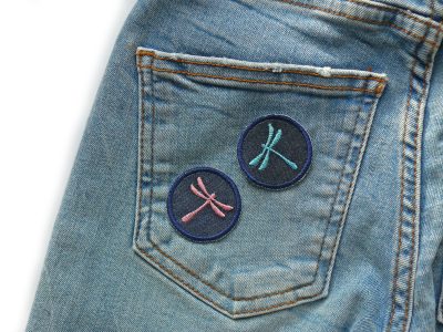 Libellen-Aufnäher auf Gesäßtasche einer Jeanshose aufgebügelt, dunkelblaue Mini-Jeansflicken Ø 4 cm mit gestickter Libelle, dekorativer Bügelflicken handmade Berlin Piratenbande