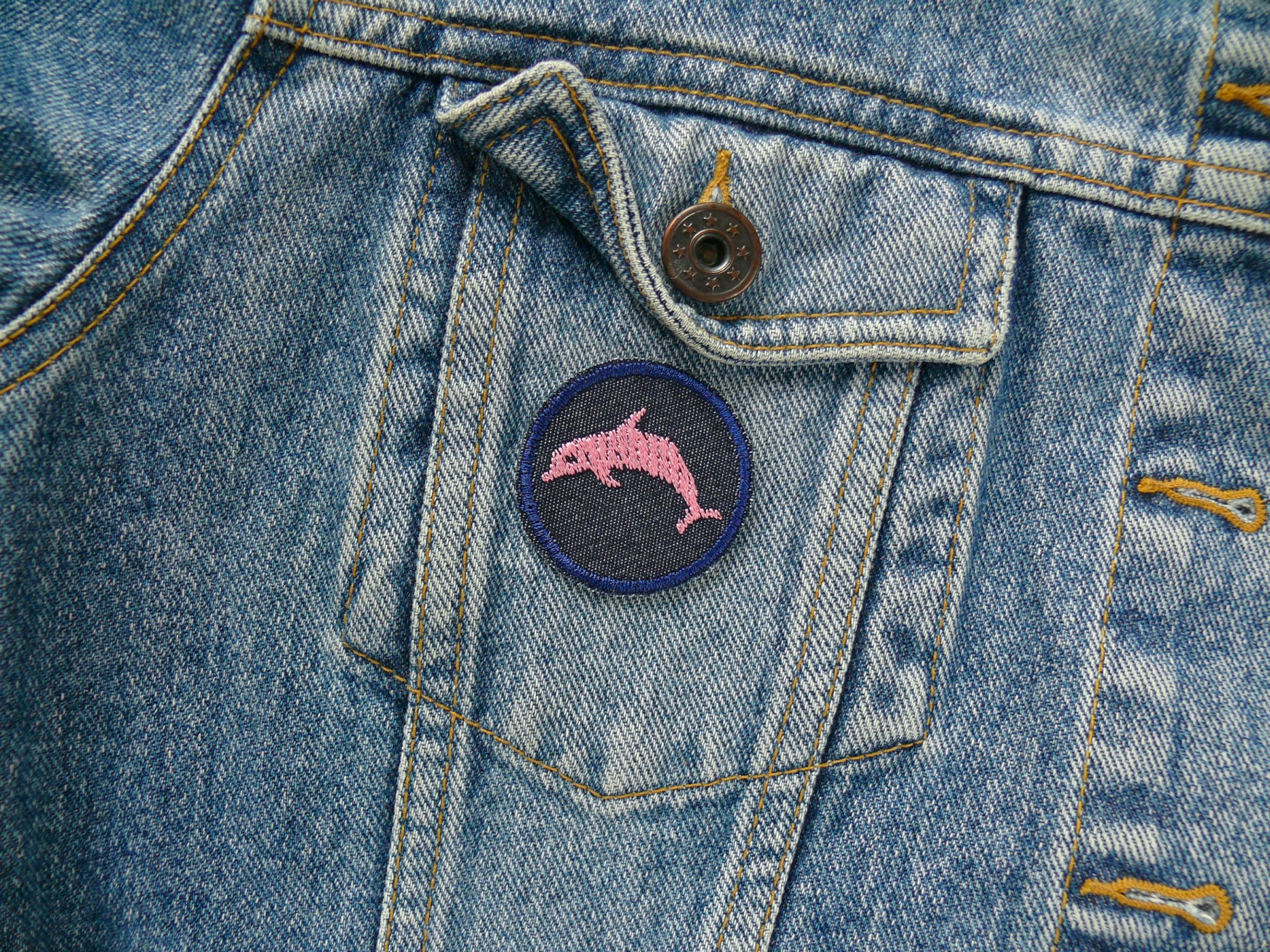 Rosa Delfin Mini-Patch auf Jeansjacke aufgebügelt, dunkelblauer Jeansstoff Ø 4 cm mit rosa Delfin-Stickerei, Mini-Bügelflicken für Jeans Shirts und Taschen handmade Berlin Piratenbande