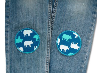Nashorn-Bügelflicken auf Kinderhose aufgebügelt, petrolgrüner Baumwollstoff Ø 8 cm mit Nashorn-Motiven in Weiß und Türkis, Hosenflicken Kinder Bügelflicken Piratenbande Berlin