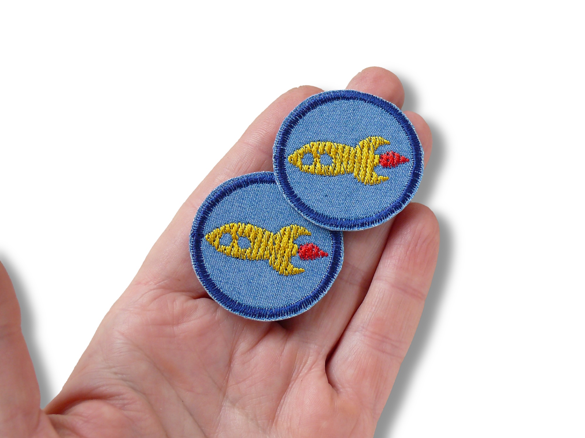 kleine Patches mit aufgestickter golbgelber Rakete auf mittelblauem Jeansstoff auf einer Handm, 4 cm Durchmesser, Handmade Piratenbande