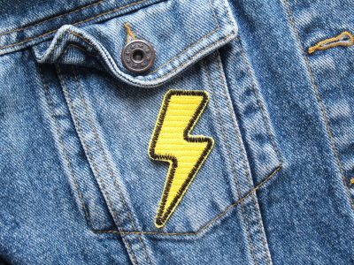 Gelber Blitz-Aufnäher auf Jeansjacke aufgebügelt, Retro Flash-Patch aus Baumwollstoff 7 x 3 cm mit schwarzer Kontur, Bügelflicken oder Statement-Patch handmade Berlin
