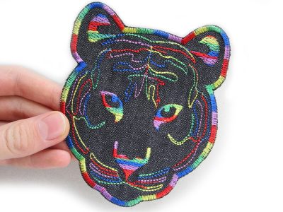 Nahaufnahme gestickter Regenbogen-Tigerkopf aus schwarzem Jeansstoff, 12 x 10 cm, bunte Stickerei Rot Orange Gelb Grün Blau Lila, XL Tiger-Aufnäher handmade Berlin